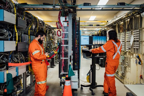 Jonathan et son collègue Kim en train de faire un entretien préventif dans une salle de réseaux et télécommunications.